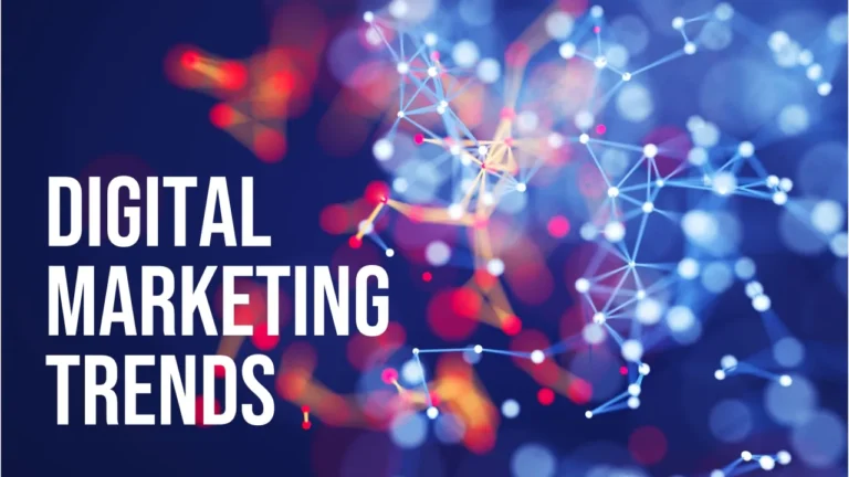 The words 'DIGITAL MARKETING' stacked and left-aligned in large, bold white sans-serif font on the left side of the image. Below, the word 'TRENDS' is in a slightly smaller, bold white sans-serif font. The background is a blurred, abstract representation of a digital network, featuring interconnected white nodes and lines against a dark blue backdrop with bokeh effects in shades of red, orange, and light blue, suggesting technology and interconnectedness in the context of marketing.